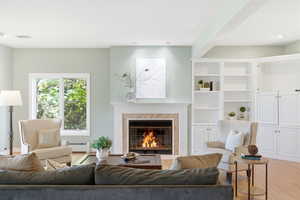 Living room featuring wood finished floors, a premium fireplace, and a baseboard heating unit