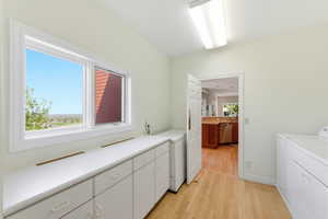 Laundry room featuring light wood-style floors and cabinet space