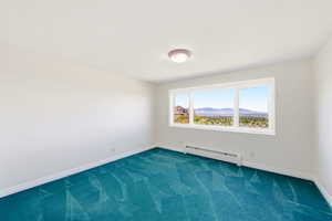Spare room featuring dark colored carpet, baseboard heating, and a mountain view