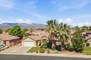 View of front of home featuring an attached garage, concrete driveway, stucco siding, a residential view, and a mountain view