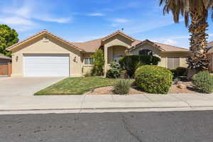 View of front of house with an attached garage, stucco siding, driveway, a front lawn, and a tiled roof