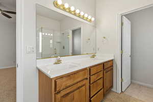 Bathroom with double vanity, a ceiling fan, a stall shower, light colored carpet, and light tile patterned floors