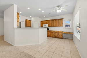 Kitchen with light tile patterned floors, light countertops, wood finish cabinetry, recessed lighting, and a ceiling fan