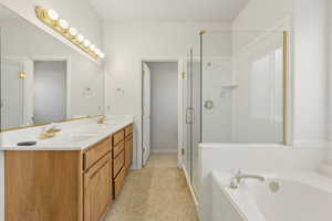 Full bathroom featuring double vanity, a stall shower, and a bath