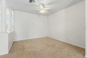 Unfurnished room with ornate columns, light carpet, and ceiling fan