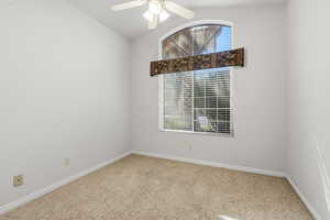 Spare room with light carpet, vaulted ceiling, and a ceiling fan