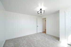 Unfurnished bedroom with light colored carpet and baseboards