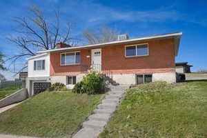 View of front of home featuring a chimney, brick siding, a front lawn, and an attached garage