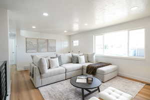 Living room featuring recessed lighting, light wood finished floors, and a textured ceiling