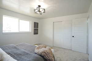 Carpeted bedroom with a closet, a textured ceiling, and suspended lighting