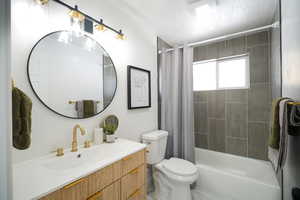 Full bathroom featuring vanity, a textured ceiling, and shower / bath combination with curtain