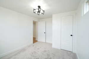 Unfurnished bedroom featuring light carpet and baseboards