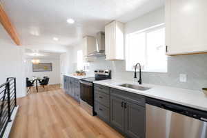 Kitchen featuring two tone cabinetry, stainless steel appliances, light wood finished floors, light stone countertops, and backsplash
