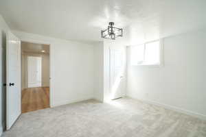 Empty room with light carpet and a textured ceiling