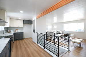Kitchen featuring two tone color scheme, beamed ceiling, black electric range, light wood finished floors, and tasteful backsplash