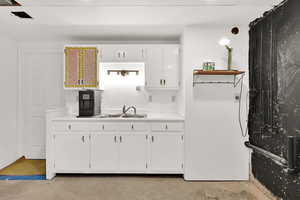 Kitchen featuring light countertops, white cabinets, and concrete floors