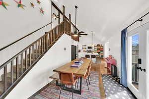 Dining area with light wood-type flooring, ceiling fan, and vaulted ceiling