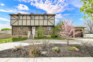 Tudor home featuring stone siding, stucco siding, driveway, and a garage