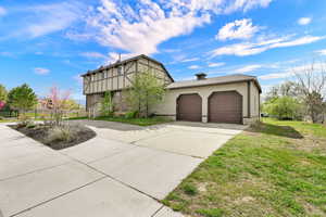 Tudor home featuring a garage, concrete driveway, and stucco siding