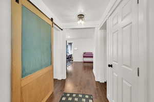 Corridor with a barn door and dark wood finished floors