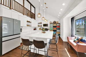Kitchen with stainless steel appliances, open shelves, white cabinetry, a kitchen island with sink, and vaulted ceiling