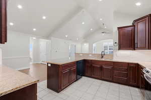 Kitchen with a peninsula, arched walkways, light stone counters, decorative backsplash, and black dishwasher