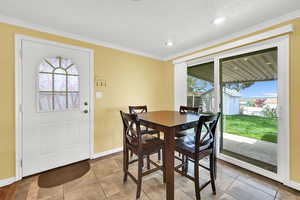 Dining area with crown molding, light tile patterned flooring, and recessed lighting