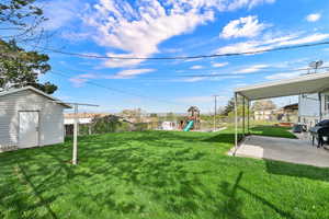 Fenced backyard featuring a patio, an outbuilding, and a playground