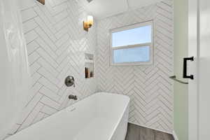 Full bath with a freestanding bath, wood finished floors, and a shower with shower curtain