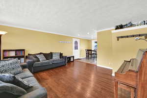 Living room featuring dark wood-style flooring, crown molding, recessed lighting, and a textured ceiling