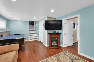 Game room with a fireplace, dark wood-type flooring, and recessed lighting