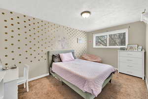 Bedroom with wallpapered walls, light colored carpet, and a textured ceiling