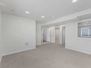 Unfurnished room featuring light colored carpet, a textured ceiling, and recessed lighting