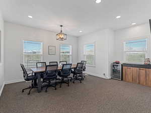 Office with beverage cooler, dark carpet, plenty of natural light, recessed lighting, and a textured ceiling