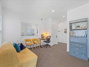 Living area with dark colored carpet, recessed lighting, and an office area