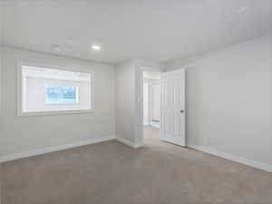 Empty room with baseboards and dark carpet
