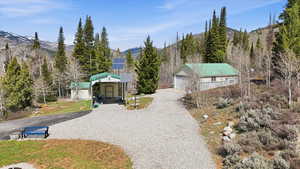View of front facade featuring solar panels, a mountain view, an outbuilding, gravel driveway, and a garage