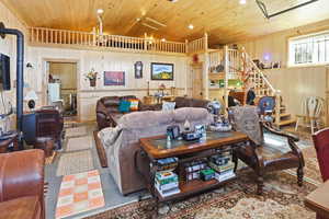 Living room featuring a wood stove, wood walls, and wooden ceiling