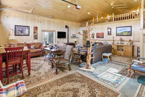 Living room featuring wood walls, wooden ceiling, and finished concrete floors