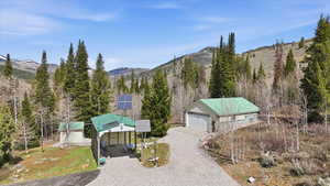 View of front of house featuring solar panels, an outbuilding, a mountain view, a detached garage, and driveway