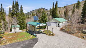 View of grassy yard with an outbuilding, a mountain view, and gravel driveway