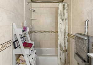 Bathroom with shower / bath combo and tile walls