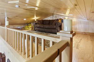 Living area featuring light wood-type flooring, wooden walls, and wood ceiling