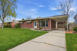 Ranch-style home featuring concrete driveway, brick siding, and a carport