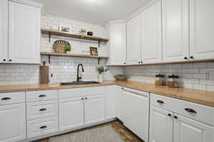 Kitchen with wood counters, white cabinets, and dishwasher