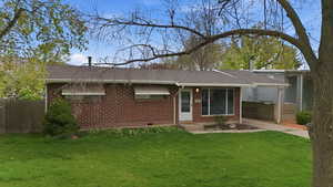 View of front facade featuring brick siding, roof with shingles, and crawl space
