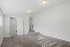 Family room with lofted ceiling, light colored carpet, and ensuite bathroom