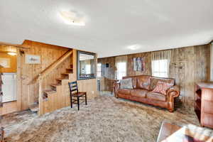Living area with light carpet, wood walls, washer / clothes dryer, and a textured ceiling
