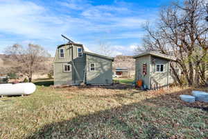 Rear view of house with a yard, a storage unit, and a gambrel roof
