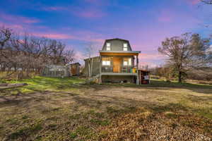 Back of house at dusk featuring a yard, an outbuilding, a greenhouse, and a sunroom